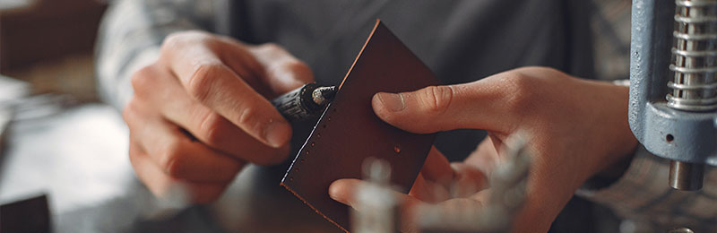 Foto: Zwei Hände bearbeiten ein Stück Metall