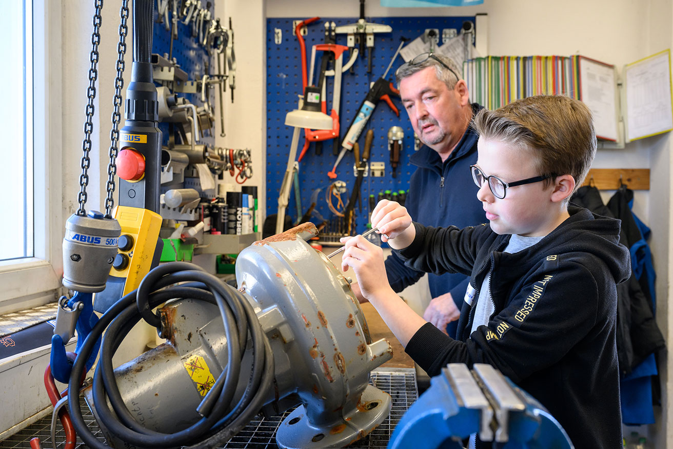 Foto: Ein Mann zeigt einem Schüler ein technisches Gerät.