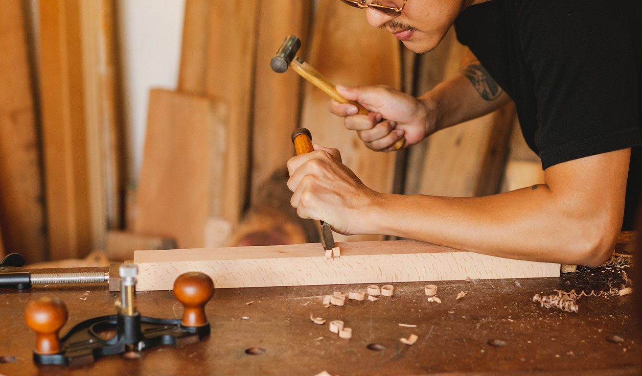 Foto: Ein Mann arbeitet mit Holzfeile und Hammer