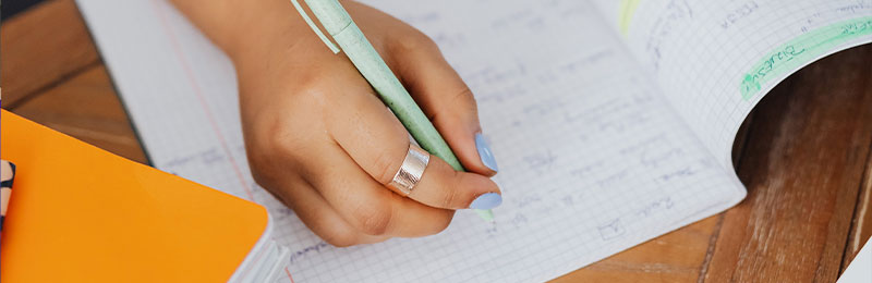 Foto: Eine Hand schreibt in ein Notizbuch.