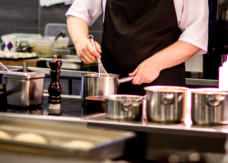 Foto: Person rührt mit Schneebesen in einem Topf.