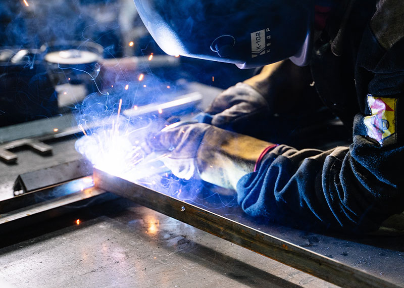 Foto: Ein Arbeiter schweißt Metall in einer Werkstatt.
