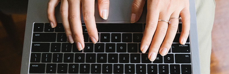 Foto: Hände tippen auf einer Laptop-Tastatur.