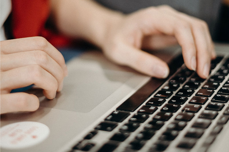 Foto: Hände tippen auf einer Laptop-Tastatur.