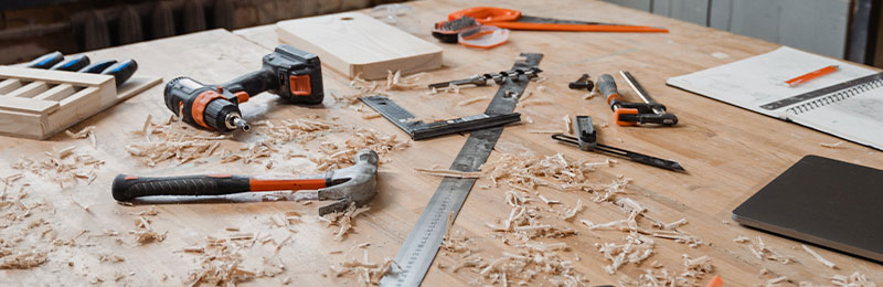 Foto: Eine Sammlung von Handwerkzeugen und Sägemehl verteilt auf einem Tisch.