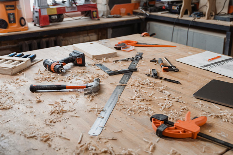 Foto: Eine Sammlung von Handwerkzeugen und Sägemehl verteilt auf einem Tisch.