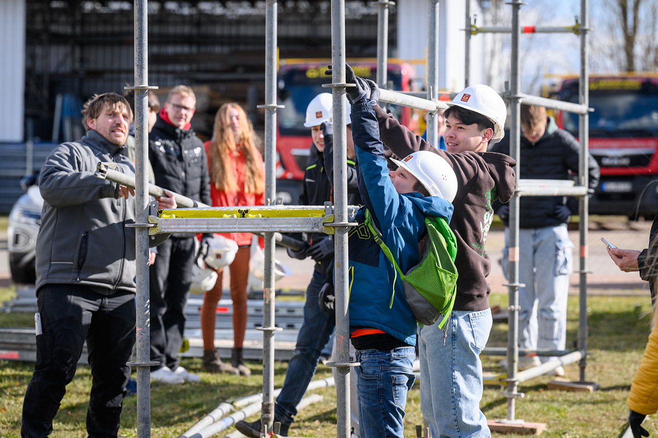 Foto: Jugendliche bauen ein Gerüst auf.