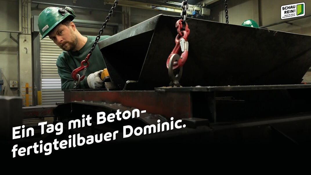 Foto: Ein Arbeiter mir Helm in einer Werkstatt, der einen Metallbehälter an Ketten hält und Text: Ein Tag mit Betonfertigteilbauer Dominic