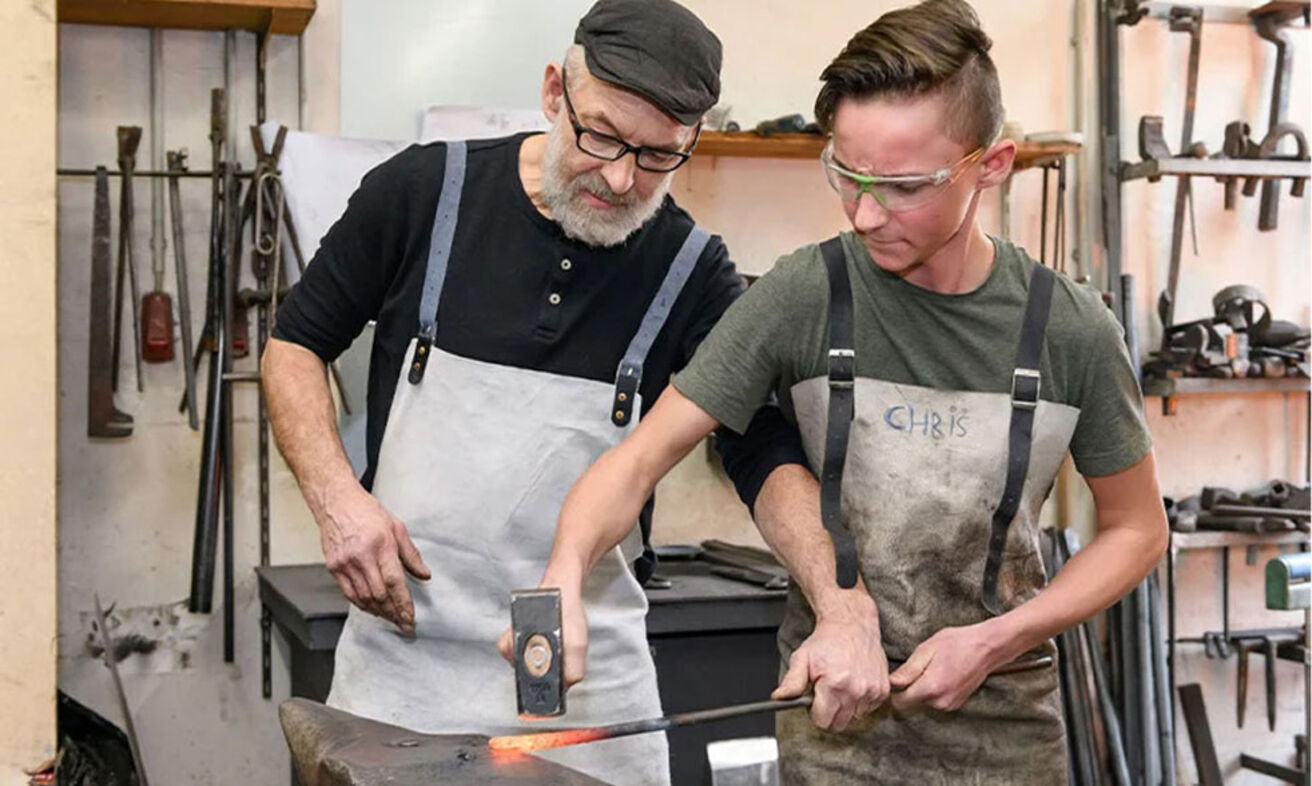 Foto: Ein Mann und ein Junge schmieden in der Werkstatt.